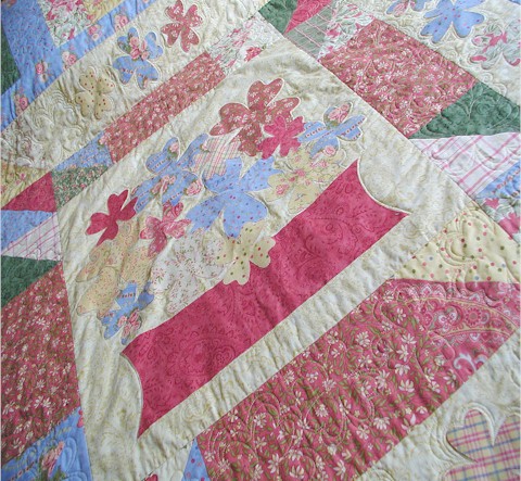 The quilting motifs on the quilt are repeats of the applique flowers in